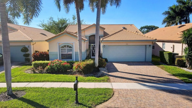 view of front of home featuring stucco siding, a garage, a tiled roof, decorative driveway, and brick siding