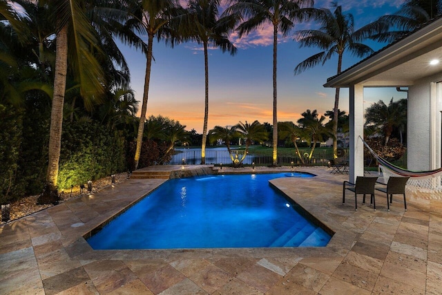 pool at dusk featuring a fenced in pool, a patio area, and fence