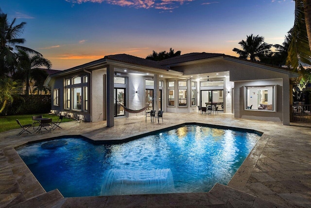 pool at dusk featuring an outdoor pool and a patio area