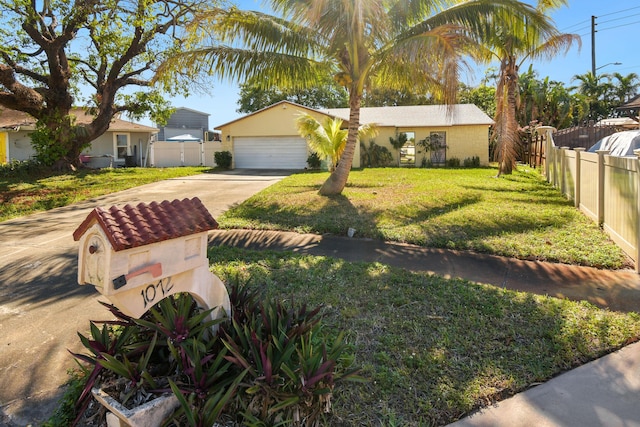 view of front of house with concrete driveway, an attached garage, fence, and a front yard