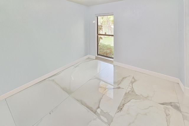 spare room with baseboards and marble finish floor