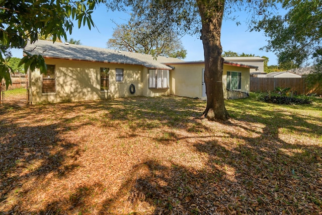 rear view of property featuring a yard and fence