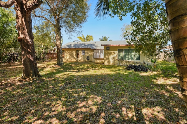 exterior space with stucco siding, a yard, and fence