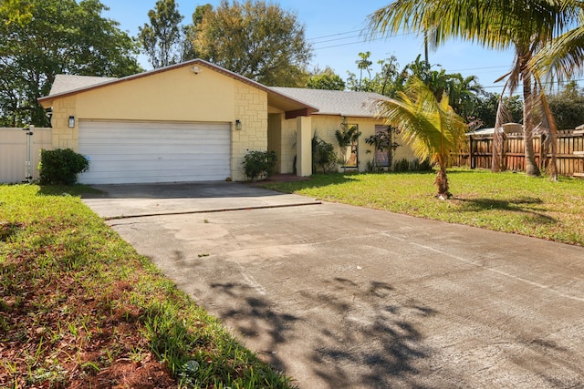 view of front of property with a front yard, an attached garage, fence, and stucco siding