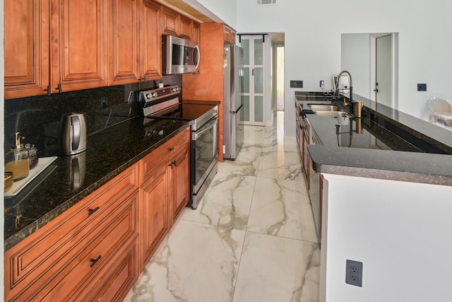 kitchen featuring visible vents, appliances with stainless steel finishes, brown cabinetry, marble finish floor, and a sink