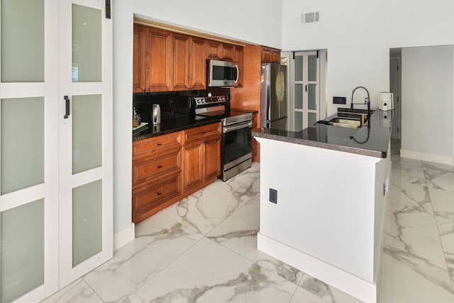 kitchen featuring a sink, dark countertops, marble finish floor, and appliances with stainless steel finishes