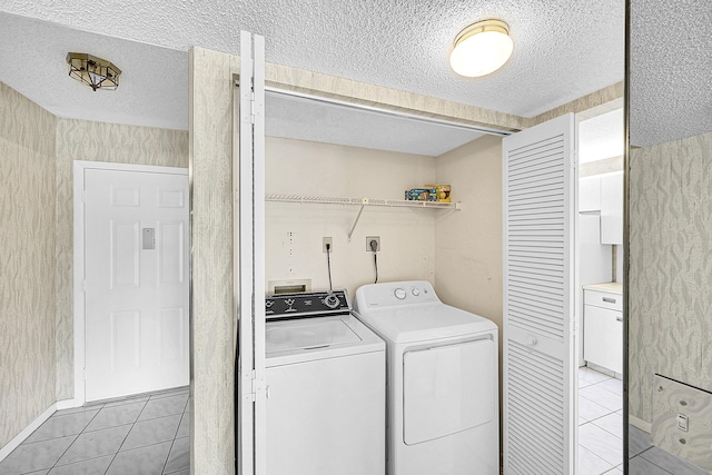 laundry area with washing machine and clothes dryer, laundry area, a textured ceiling, and light tile patterned floors