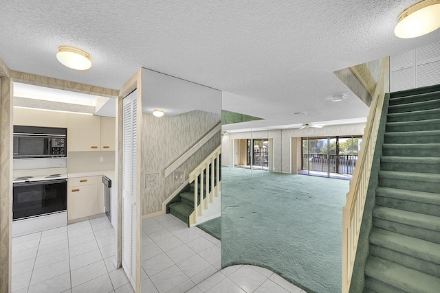 stairway with tile patterned floors, carpet, a ceiling fan, and a textured ceiling