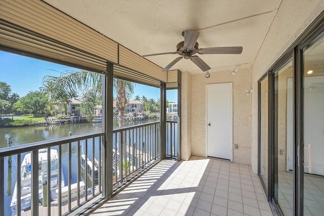 unfurnished sunroom featuring a ceiling fan and a water view