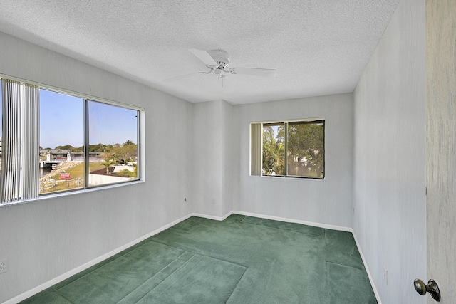 empty room featuring baseboards, a textured ceiling, carpet, and a ceiling fan