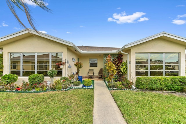 ranch-style home with a front yard and stucco siding