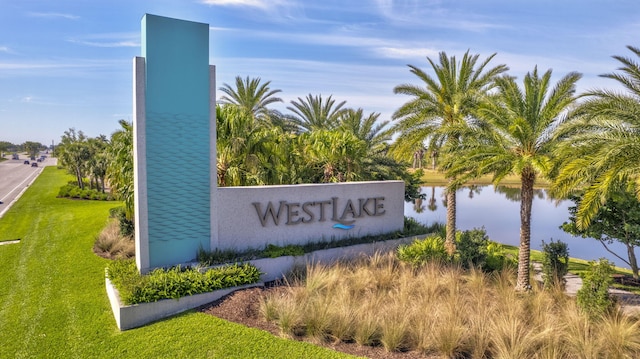 community sign featuring a lawn and a water view