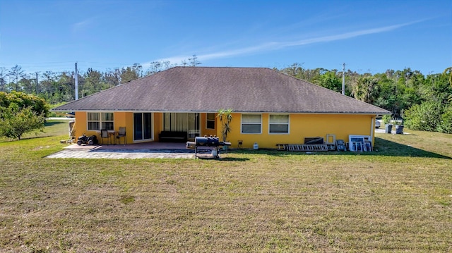 back of property with stucco siding, a patio, a yard, and roof with shingles