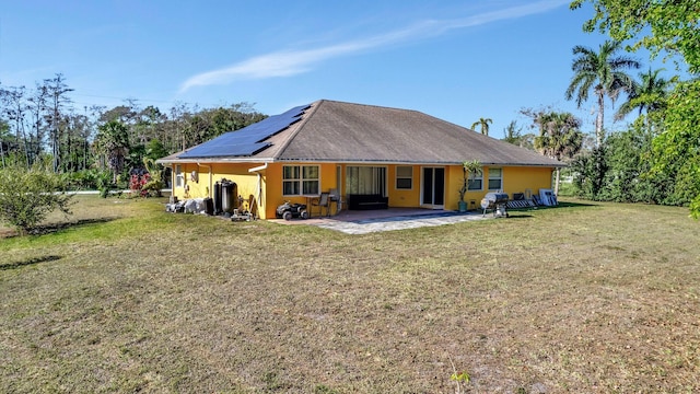 rear view of property with a yard, a patio, solar panels, and stucco siding