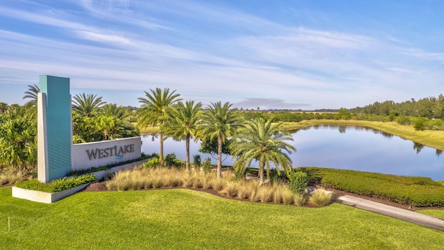 community / neighborhood sign featuring a lawn and a water view