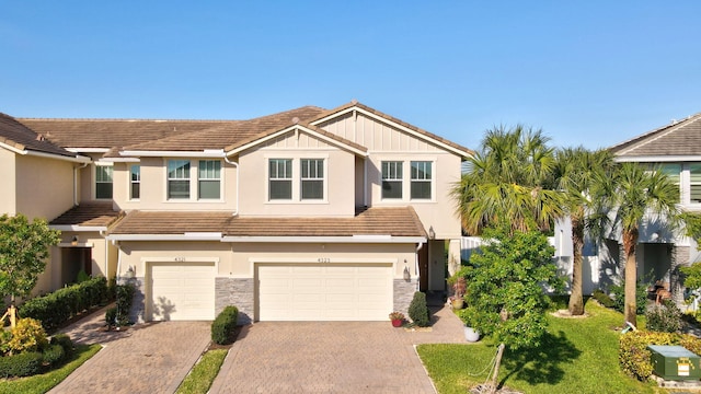 4323 Veleiros Ave, Deerfield Beach, FL 33064 - view of front facade featuring stucco siding, driveway, stone siding, a garage, and a tiled roof