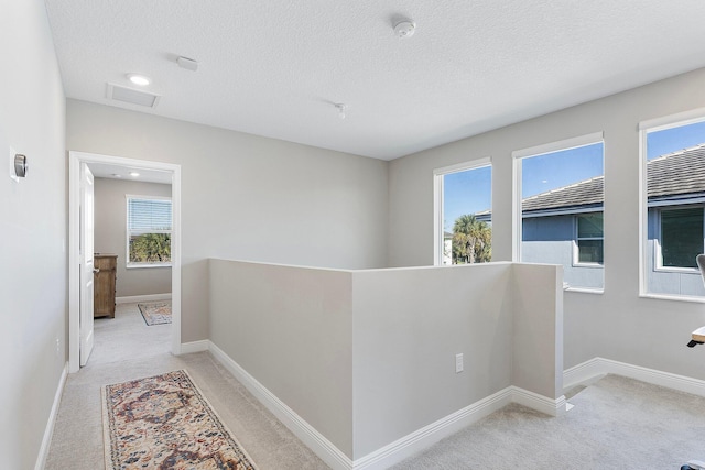 hall with an upstairs landing, visible vents, baseboards, and carpet