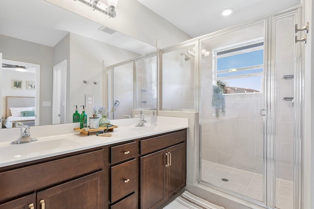 full bath with double vanity, visible vents, a shower stall, and a sink