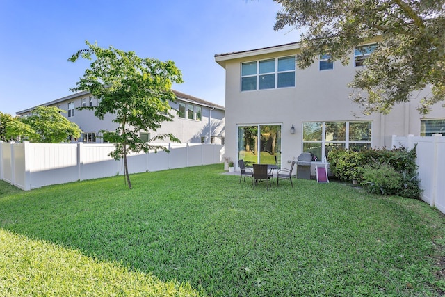 back of house featuring a yard, a fenced backyard, and stucco siding