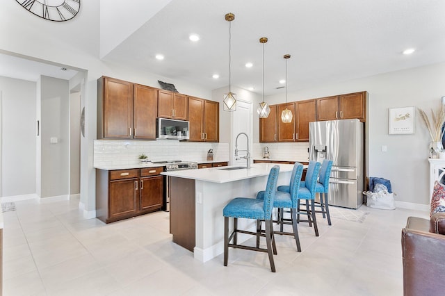 kitchen featuring a breakfast bar, a sink, light countertops, appliances with stainless steel finishes, and backsplash