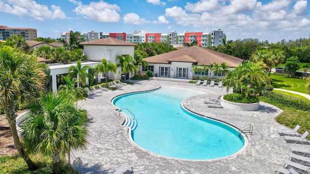 community pool with a view of city, fence, and a patio area