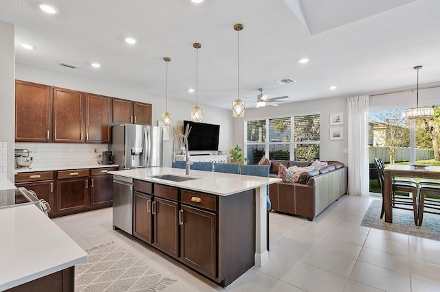 kitchen with visible vents, a sink, appliances with stainless steel finishes, light countertops, and decorative backsplash