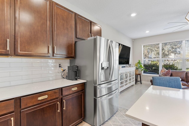 kitchen featuring backsplash, stainless steel fridge, light countertops, and ceiling fan