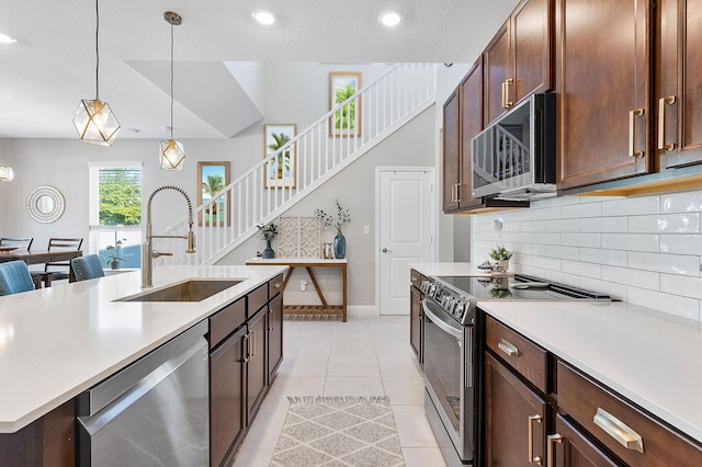 kitchen featuring light countertops, light tile patterned floors, hanging light fixtures, stainless steel appliances, and a sink