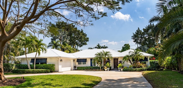 ranch-style home featuring concrete driveway, an attached garage, and a front yard