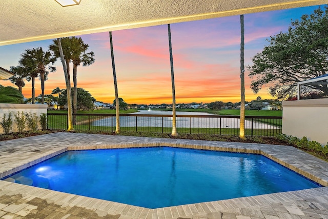 pool at dusk featuring a fenced in pool, a water view, a patio area, and fence