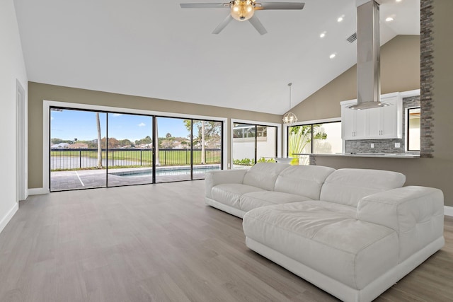 living area featuring visible vents, high vaulted ceiling, light wood-type flooring, and baseboards