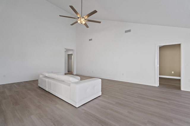 unfurnished living room featuring a ceiling fan, wood finished floors, visible vents, baseboards, and vaulted ceiling