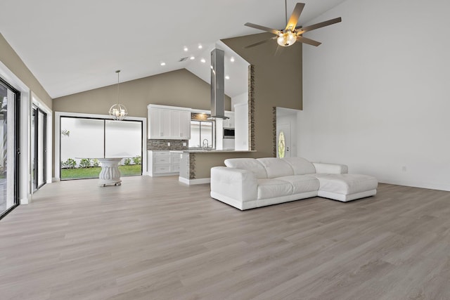 unfurnished living room with recessed lighting, light wood-style flooring, ceiling fan with notable chandelier, and a healthy amount of sunlight