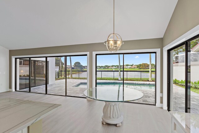 dining space with a wealth of natural light, a chandelier, lofted ceiling, and wood finished floors