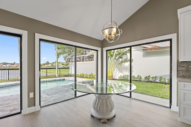 unfurnished dining area featuring light wood-type flooring, an inviting chandelier, and vaulted ceiling