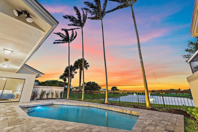 pool at dusk with a patio area, a fenced in pool, and fence