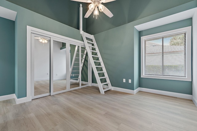 empty room with stairway, a ceiling fan, baseboards, and wood finished floors