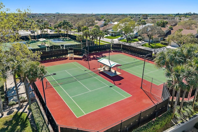 view of tennis court with a residential view and fence