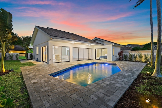 back of house featuring stucco siding, a gate, fence, a fenced in pool, and a patio area