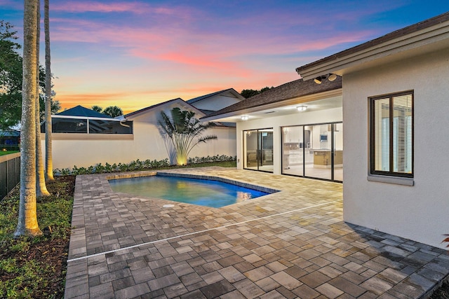 pool at dusk featuring a fenced in pool, fence, and a patio area