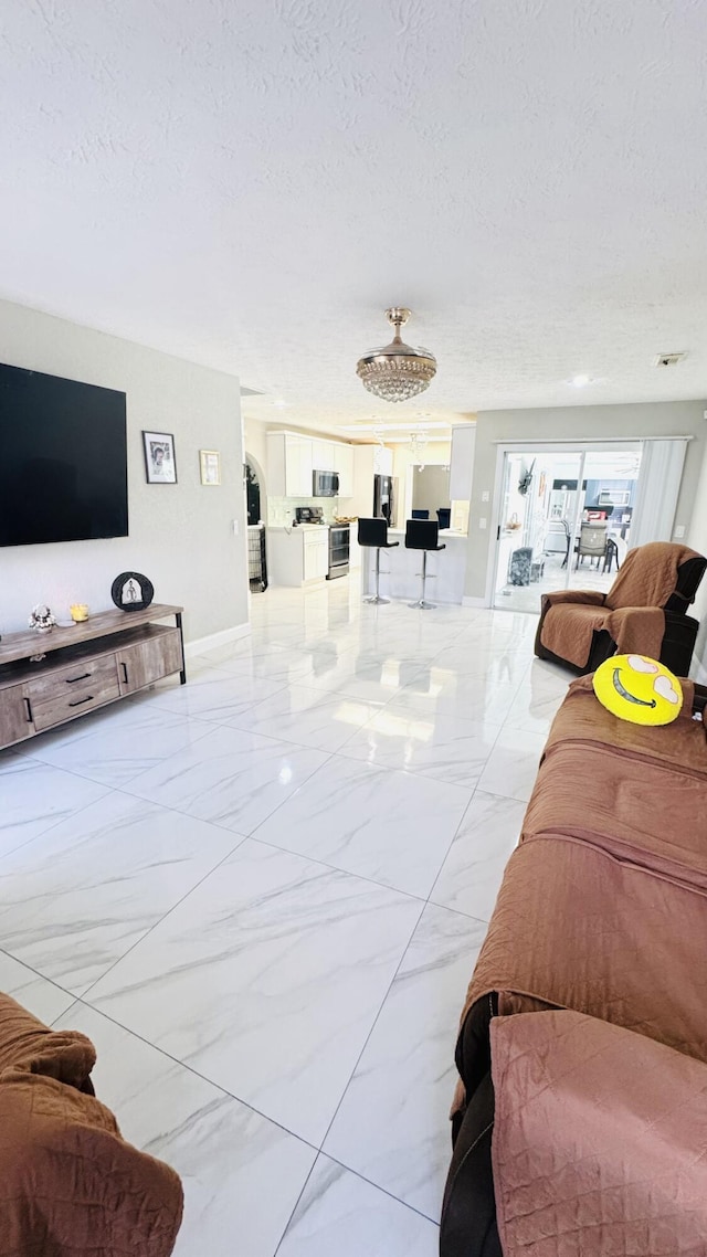 living area featuring baseboards, marble finish floor, and a textured ceiling