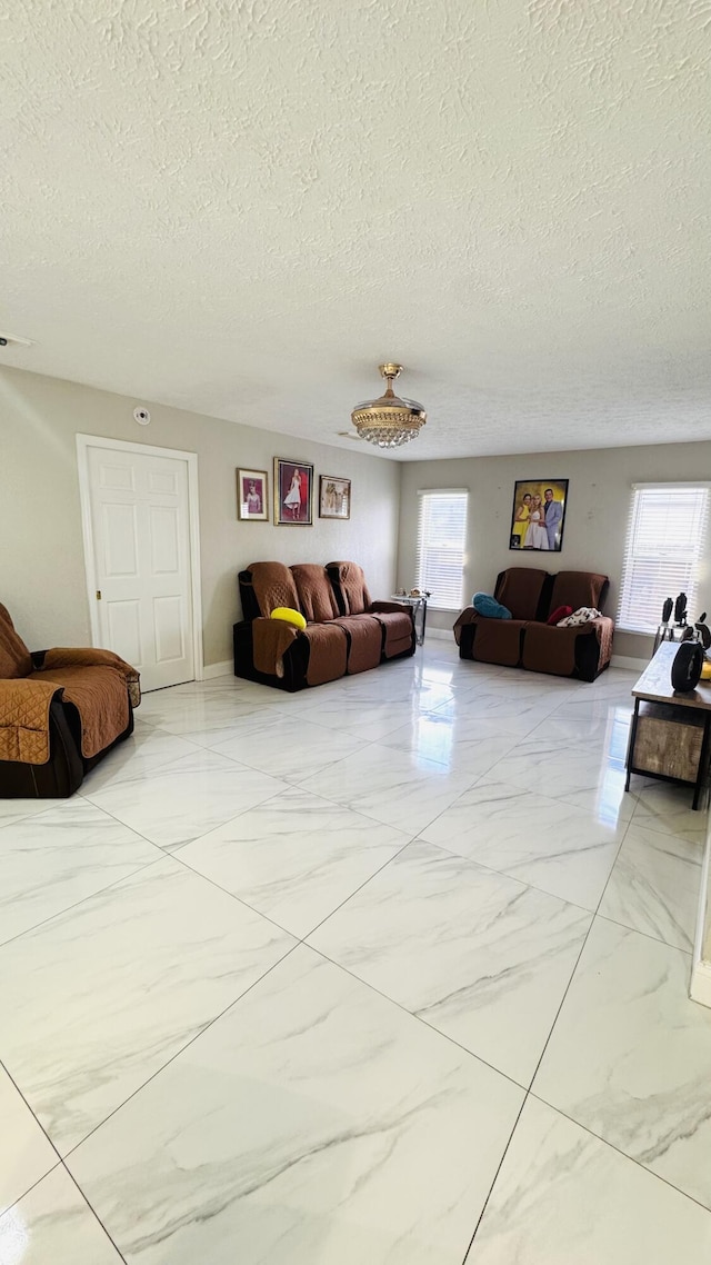 living room featuring a wealth of natural light, a textured ceiling, and marble finish floor