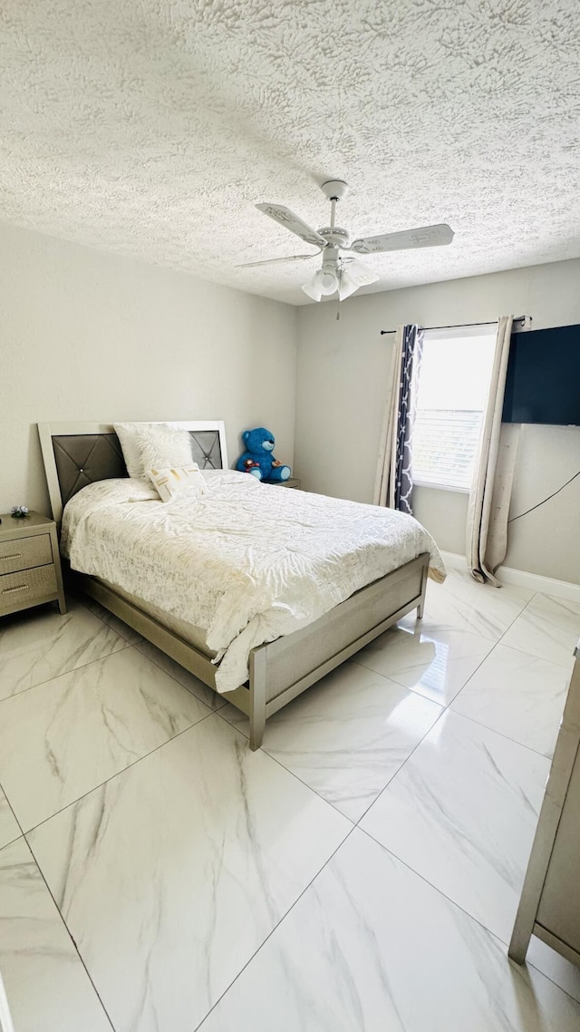 bedroom with a textured ceiling, marble finish floor, and ceiling fan