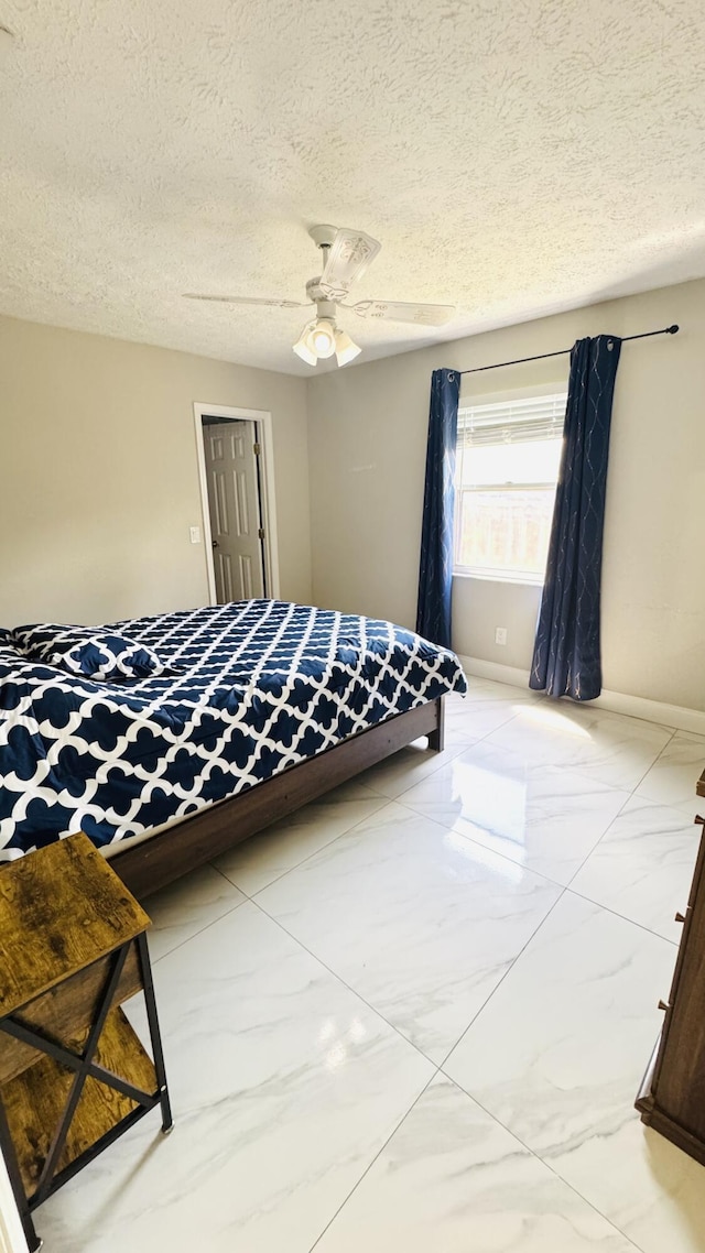 bedroom with marble finish floor, a textured ceiling, baseboards, and a ceiling fan