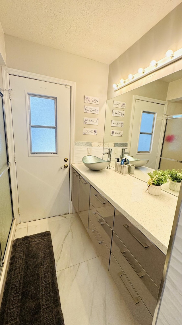 bathroom with marble finish floor, a stall shower, vanity, and a textured ceiling