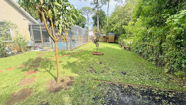 view of yard featuring glass enclosure, a fenced backyard, and a fenced in pool