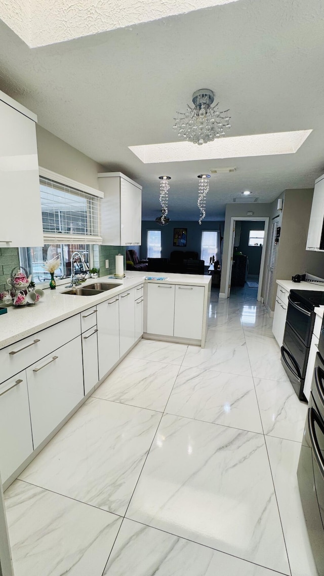 kitchen featuring a peninsula, a skylight, black range with electric stovetop, and marble finish floor