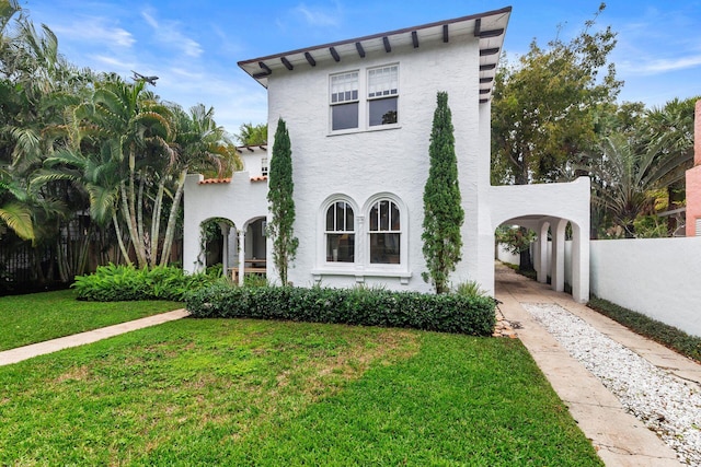 view of front of house featuring stucco siding, driveway, a front yard, and fence