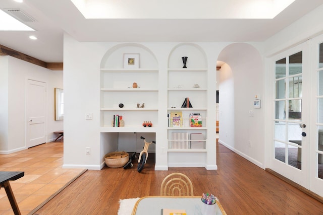 interior space with built in shelves, wood finished floors, visible vents, baseboards, and arched walkways