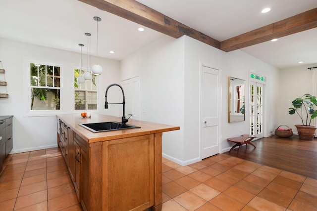 kitchen with beamed ceiling, a sink, recessed lighting, light countertops, and light tile patterned floors